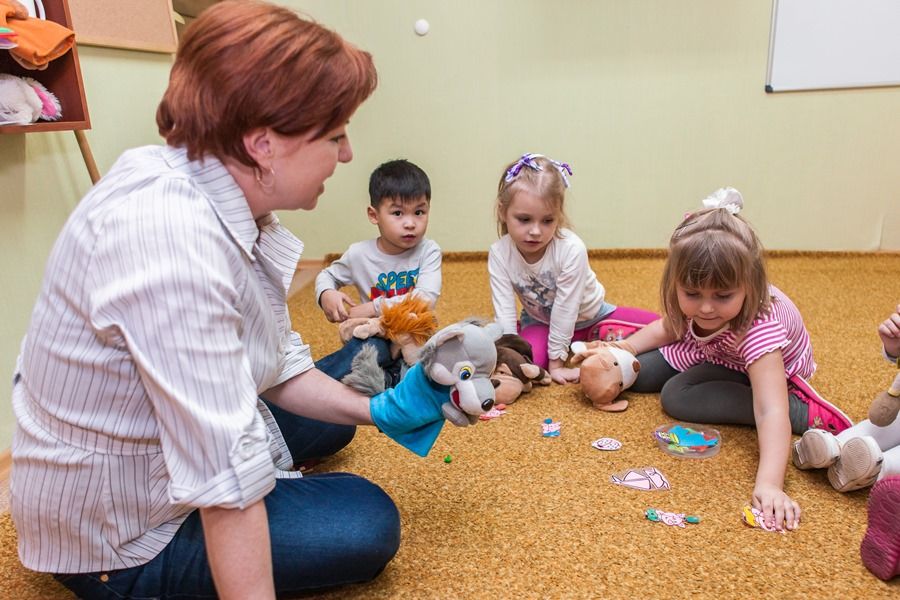 Педагог показывает детям перчаточных кукол на занятии английским языком